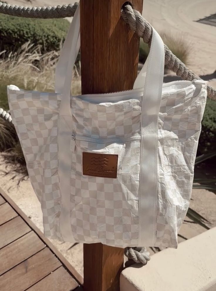 Tan Checkered Splash Proof Tote - $62 This is the perfect organizer for your day trips, sunscreen, snacks, towels, beach toys, and anything else you can think of that you want to pack in your day to day adventures. Beach ready, Sand Tested, and Water Resistant! Easy to clean-Just wipe it down. Medium 19in" x 14in" x 6" gusset Water Resistant Spill Proof 100% Tyvek technical fabric White Reusable Beach Bag, Summer Style Reusable Beach Bag For Travel, Reusable Summer Beach Bag, Summer White Beach Bag For Travel, White Summer Beach Bag For Travel, Summer Reusable Beach Bag For Travel, White Reusable Beach Bag For Travel, White Beach Bag For Summer Weekend Trips, White Beach Bag For Weekend Trips In Summer