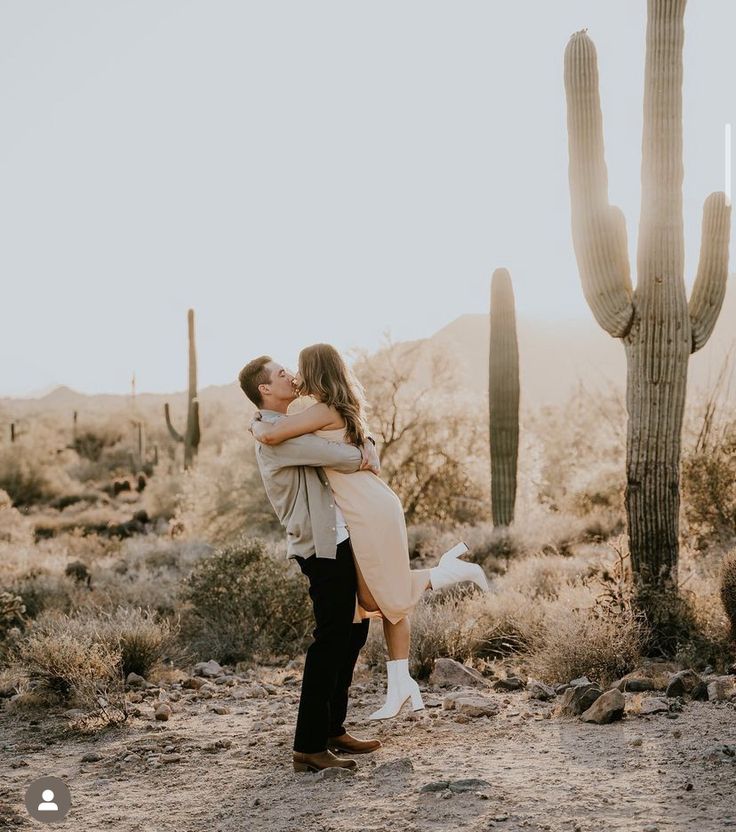 a man and woman kissing in front of a cactus