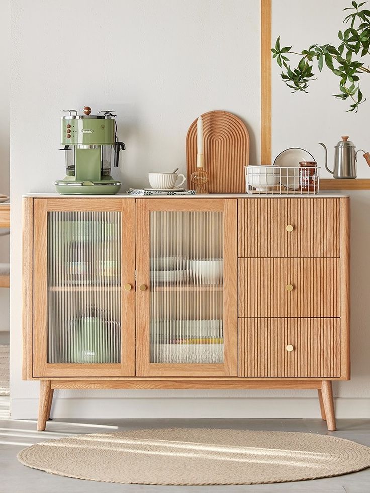 a wooden cabinet with glass doors and drawers in a living room next to a potted plant