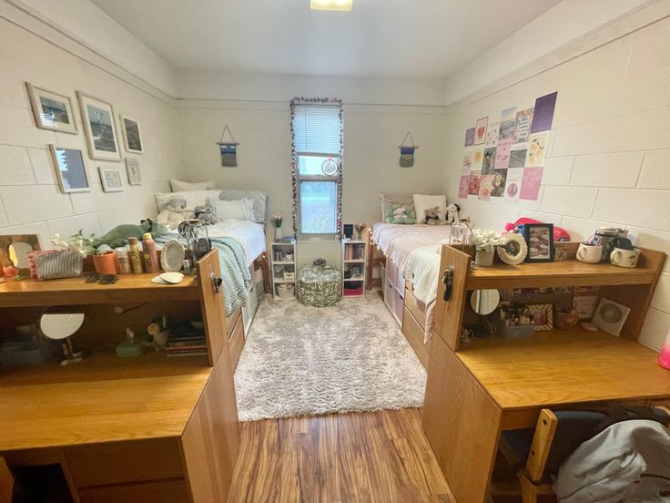 a room with two beds and desks in it