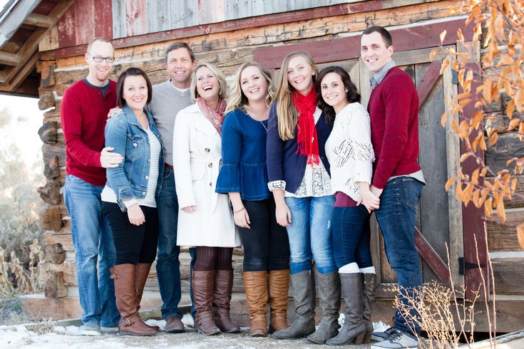 a group of people standing next to each other in front of a wooden building with snow on the ground