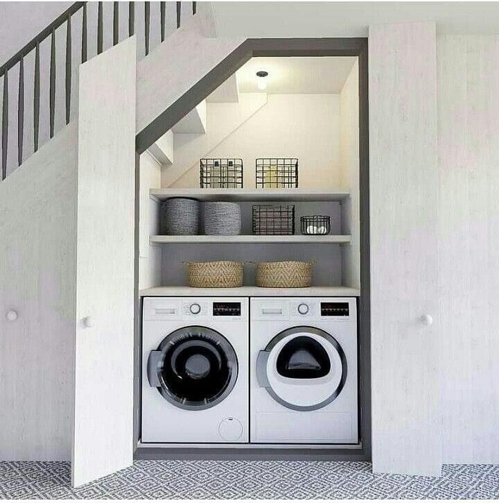 a washer and dryer in a small room with stairs leading up to the second floor