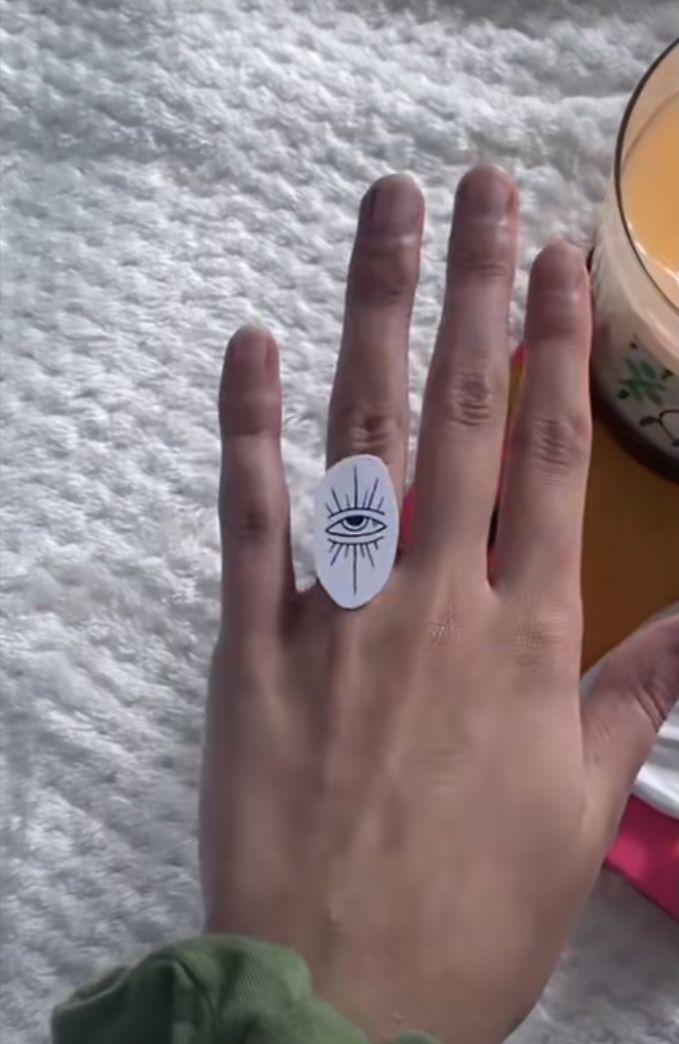 a person's hand with a ring on it next to a candle and other items