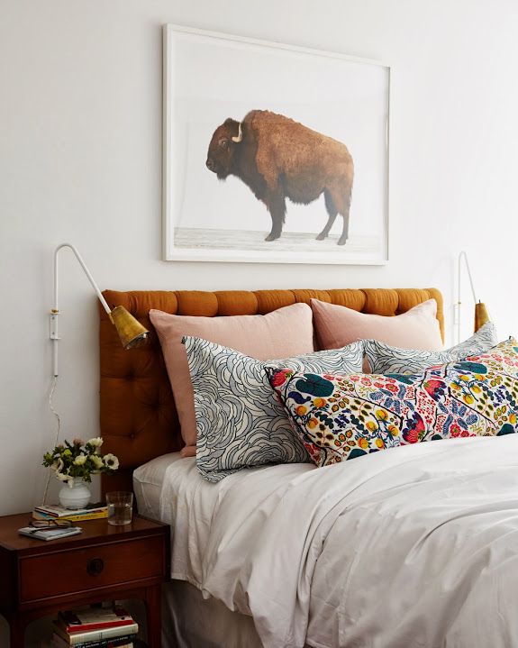 a bed topped with pillows and blankets next to a framed buffalo print on the wall