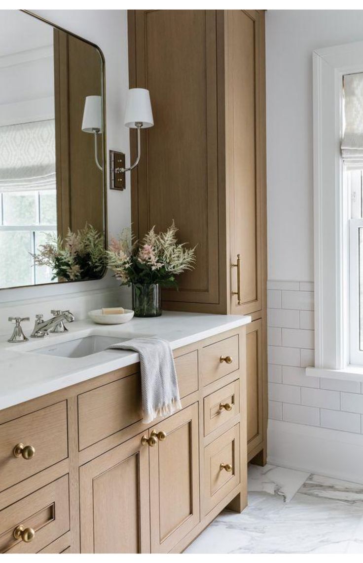 a bathroom with wooden cabinets and marble counter tops, along with white tile flooring