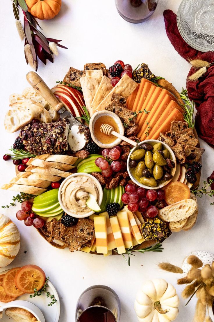 a platter filled with different types of cheeses, crackers, and fruit