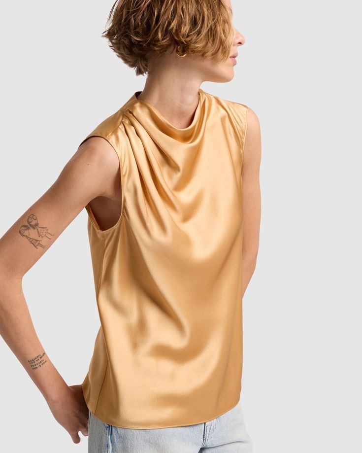 Fits like: Sleeveless shirt with draped neckline and relaxed fit. Feels like: Light and silky. The Details: 100% Silk Warm gold shade Silk Draped Blouse, Elegant Drapey Sleeveless Top, Summer Silk Draped Top, Elegant Gold Sleeveless Blouse Tank Top, Spring Gold Silk Top, Gold Silk Top For Spring, Gold Silk Tops For Spring, Chic Gold Sleeveless Top, Gold Sleeveless Blouse For Spring