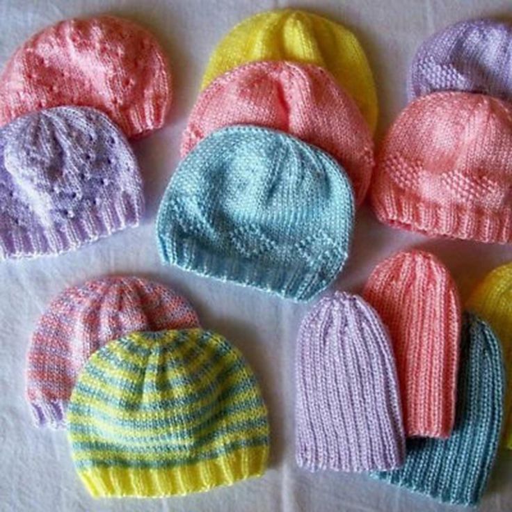 several knitted hats are arranged on a white tablecloth, one is blue and the other is pink