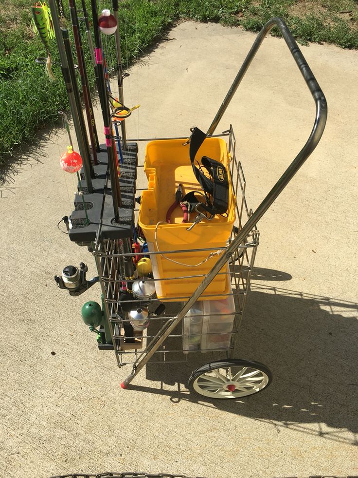 a shopping cart filled with lots of items on top of a cement road next to grass