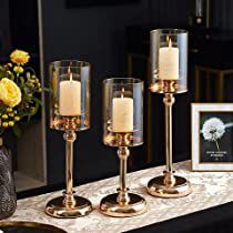 three candles are sitting on a table next to a vase with flowers and a framed photo