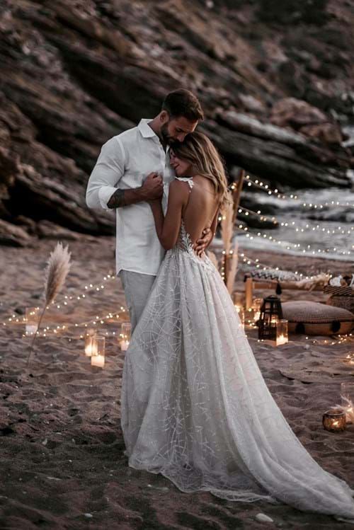 a man and woman standing next to each other in front of candles on the beach