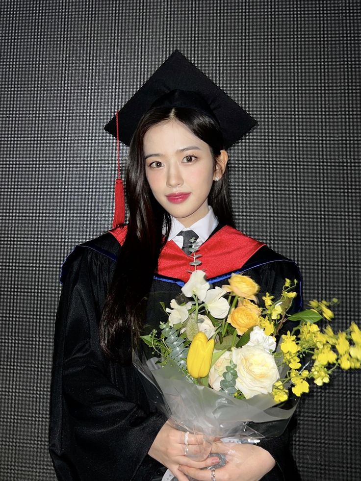 a woman in graduation gown holding flowers and wearing a black cap with yellow roses on it