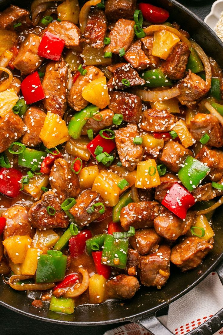 a skillet filled with meat and vegetables on top of a table