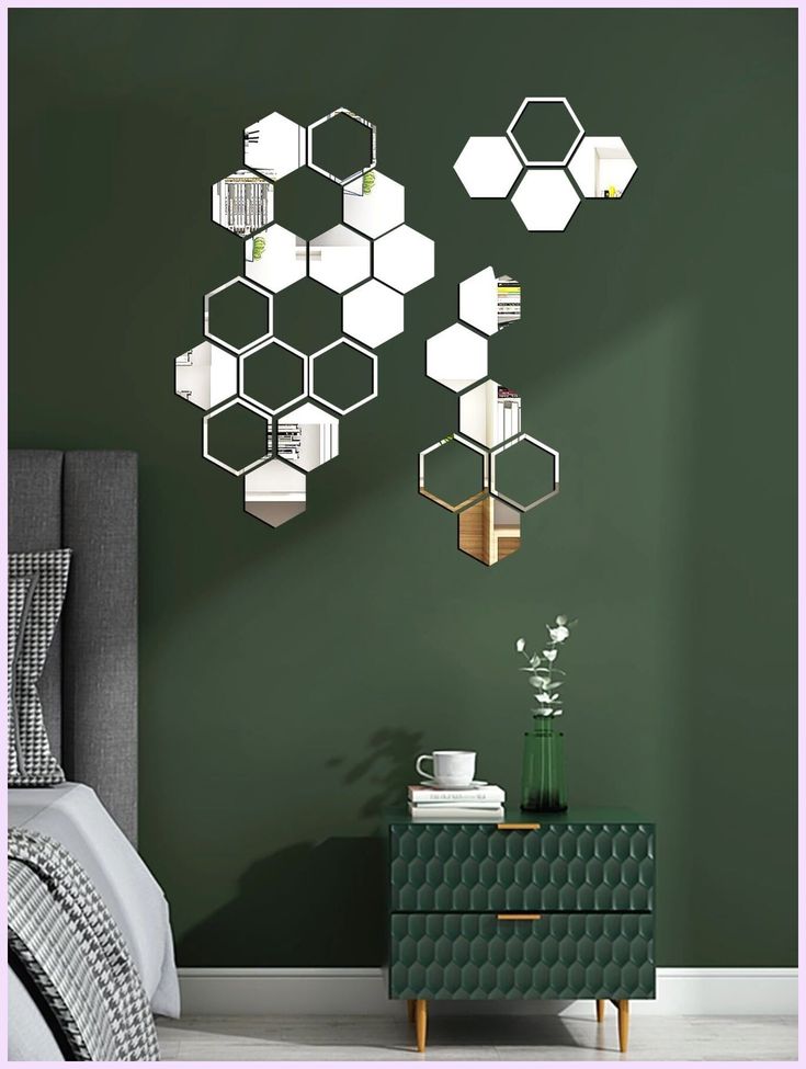 a bedroom with green walls and white hexagonal mirrors on the wall above it