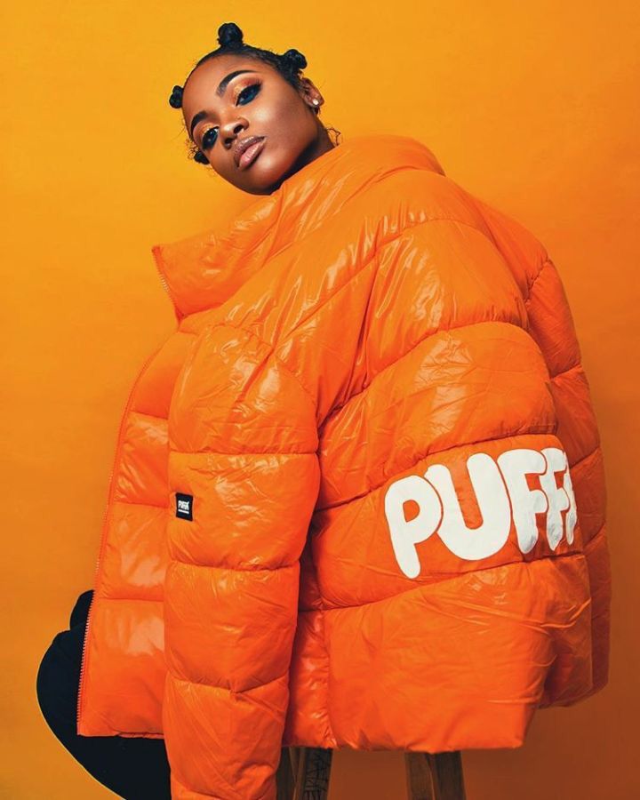 a woman in an orange puffer jacket with the word puf on her chest