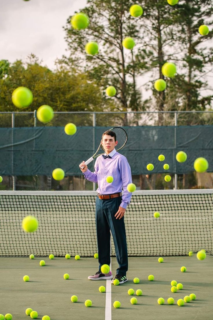 a man standing on top of a tennis court holding a racquet surrounded by balls