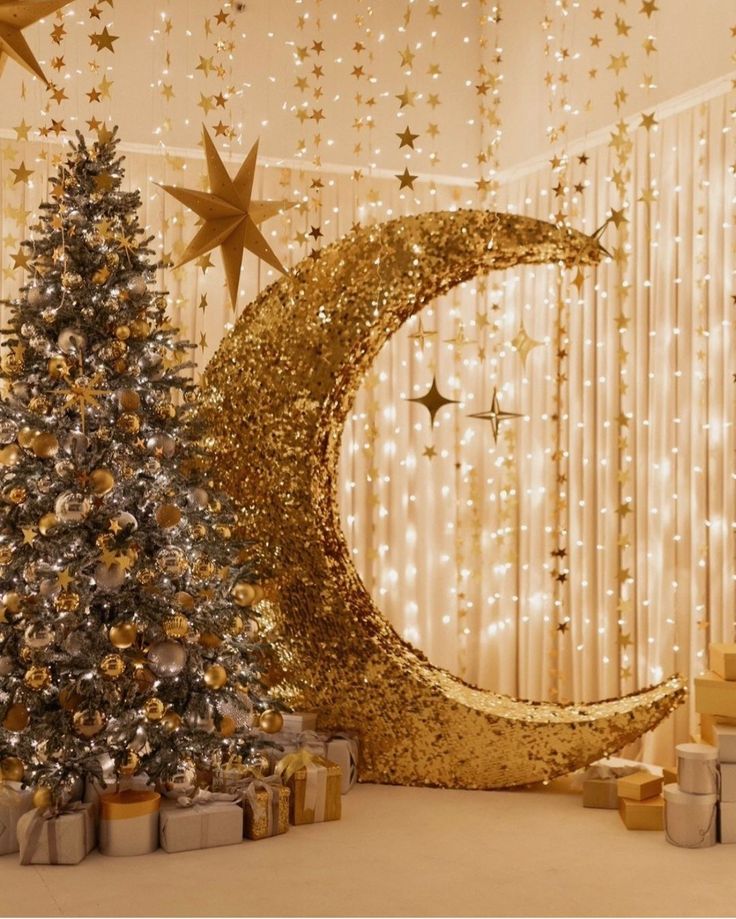 a decorated christmas tree in front of a gold moon and star wall hanging from the ceiling