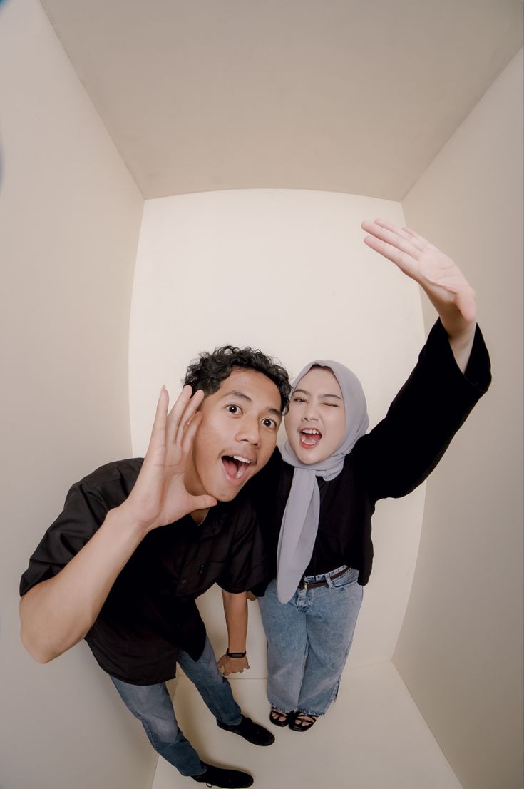 two people standing in a room with their hands up