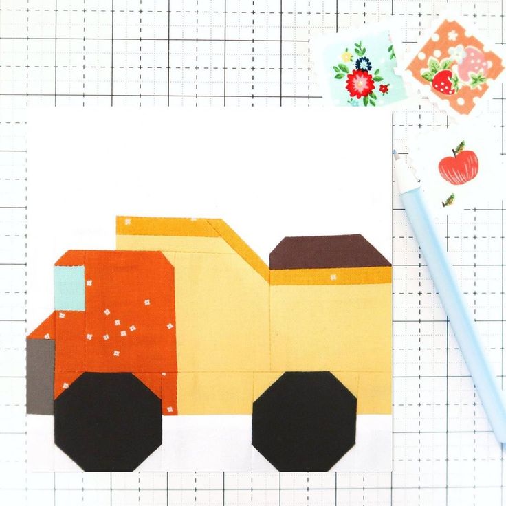 a piece of fabric with a construction truck on it and a pencil next to it