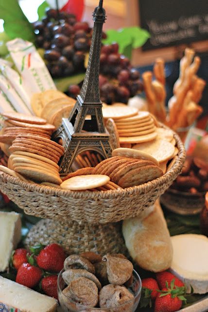 an assortment of cheeses, crackers and strawberries in front of the eiffel tower