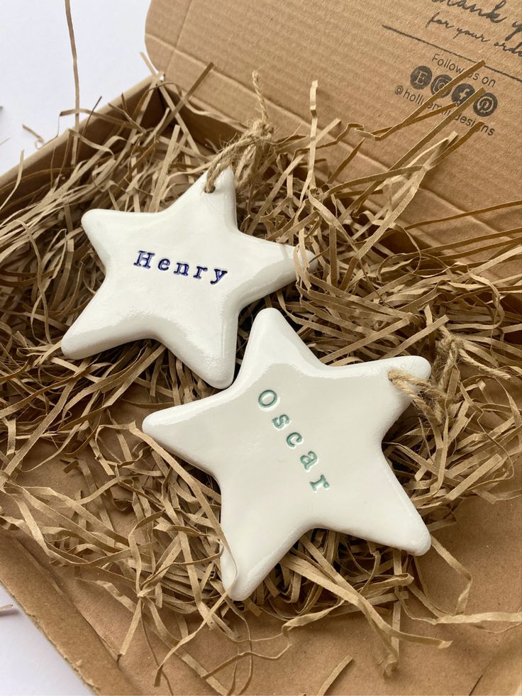 two white ceramic stars with the words henry and oscar on them in a cardboard box