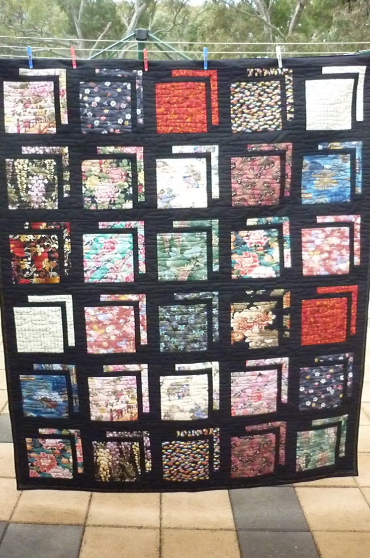 a black quilt is hanging on a clothesline with several different colored squares and designs