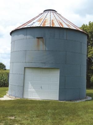 a large metal silo sitting on top of a lush green field