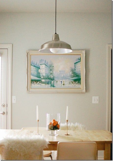 a dining room table with white chairs and a painting on the wall