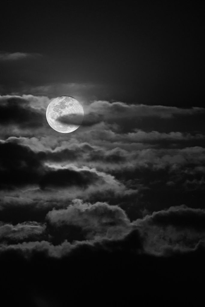 the full moon is seen through clouds in this black and white photo, taken from an airplane