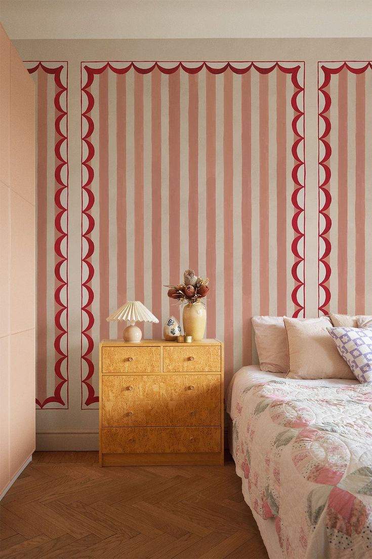 a bed sitting next to a dresser in a room with striped wall paper on the walls