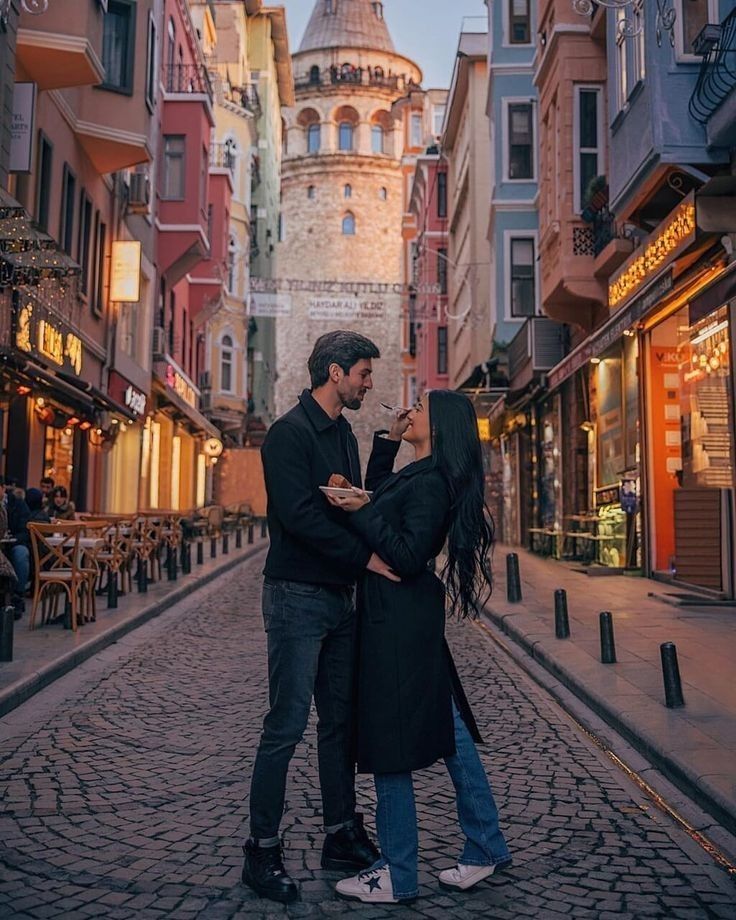 a man and woman standing in the middle of an alleyway