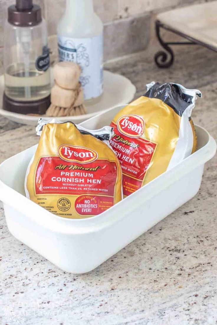 two bags of condiments sitting in a white dish on a counter top next to a bottle of mayonnaise