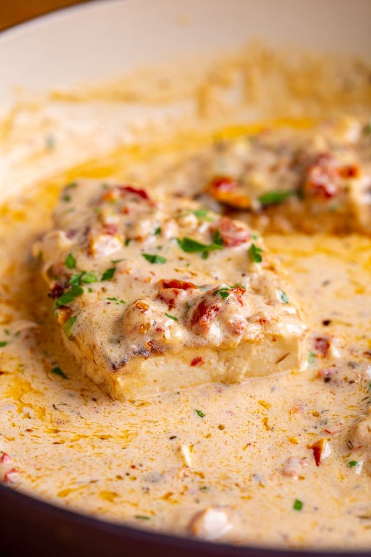 two pieces of food in a bowl with sauce and parsley on the top,