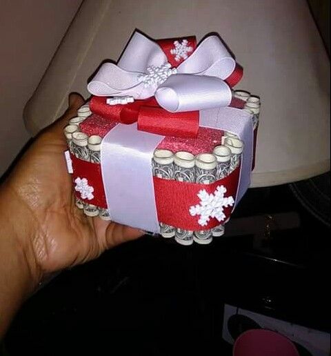 a hand holding a red and white gift box