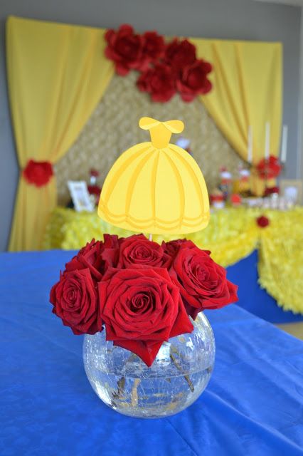 a vase filled with red roses sitting on top of a blue tablecloth covered table