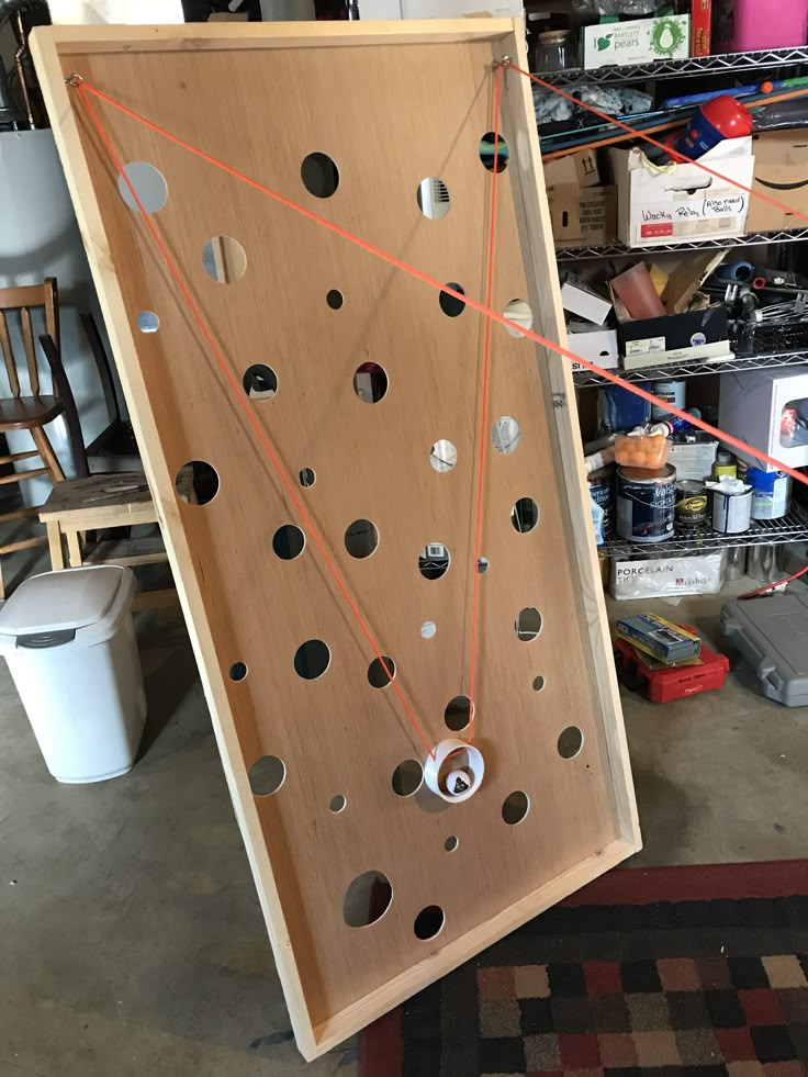 a large wooden board with holes and strings attached to it in a garage area next to other items