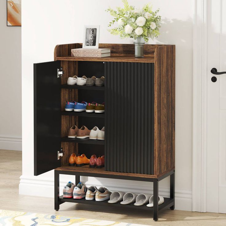 a shoe rack with shoes on it in front of a door and a flower vase