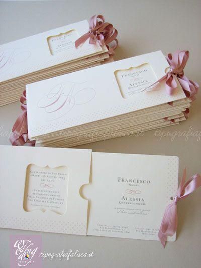 three folded wedding cards with pink bows on them, one in white and the other in gold