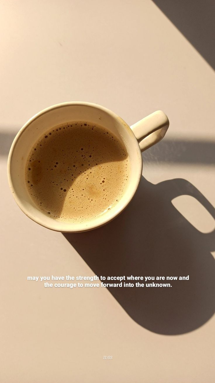 a cup of coffee sitting on top of a table next to a shadow from the sun