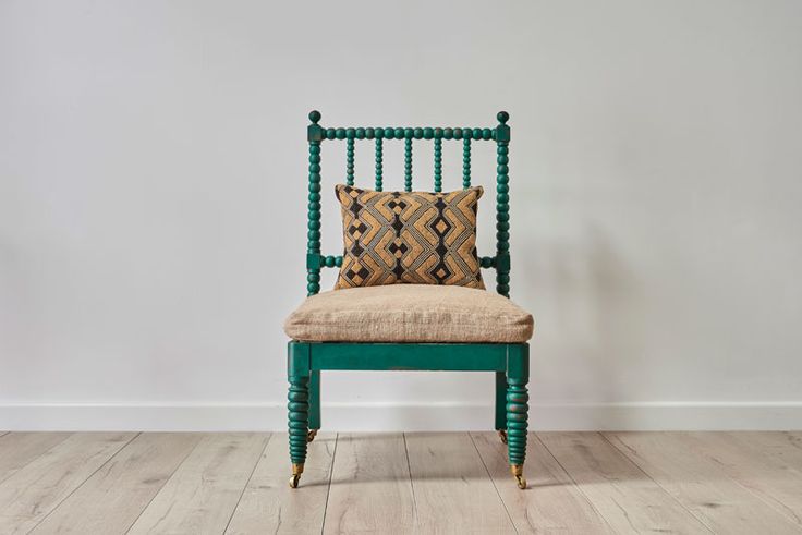 a green chair with a pillow on top of it in front of a white wall