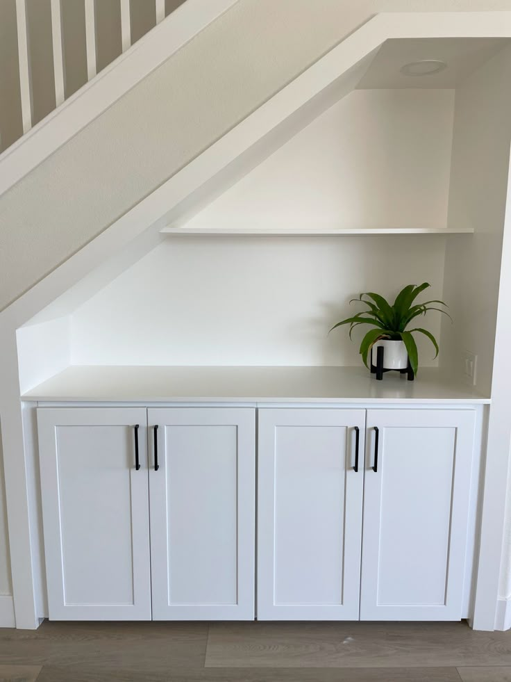 a plant is sitting on top of the cabinet under the stairs in an attic space