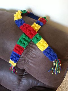 a crocheted scarf sitting on top of a brown leather couch