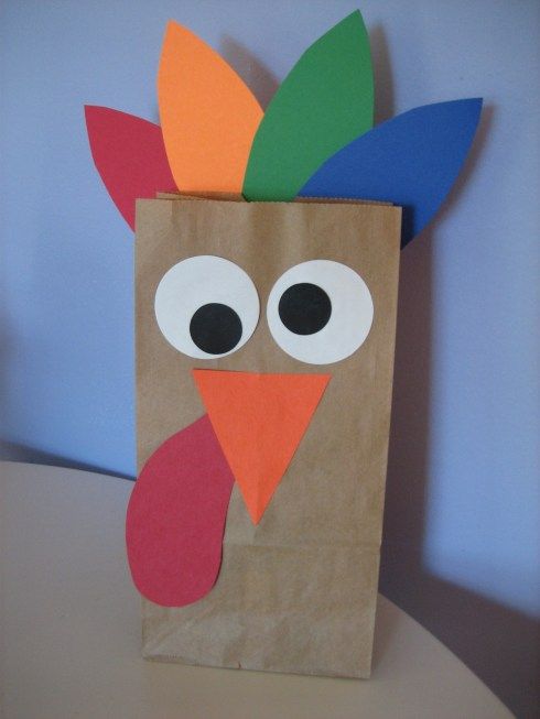 a brown paper bag with a turkey on it's side and eyes painted orange, green, blue, and red