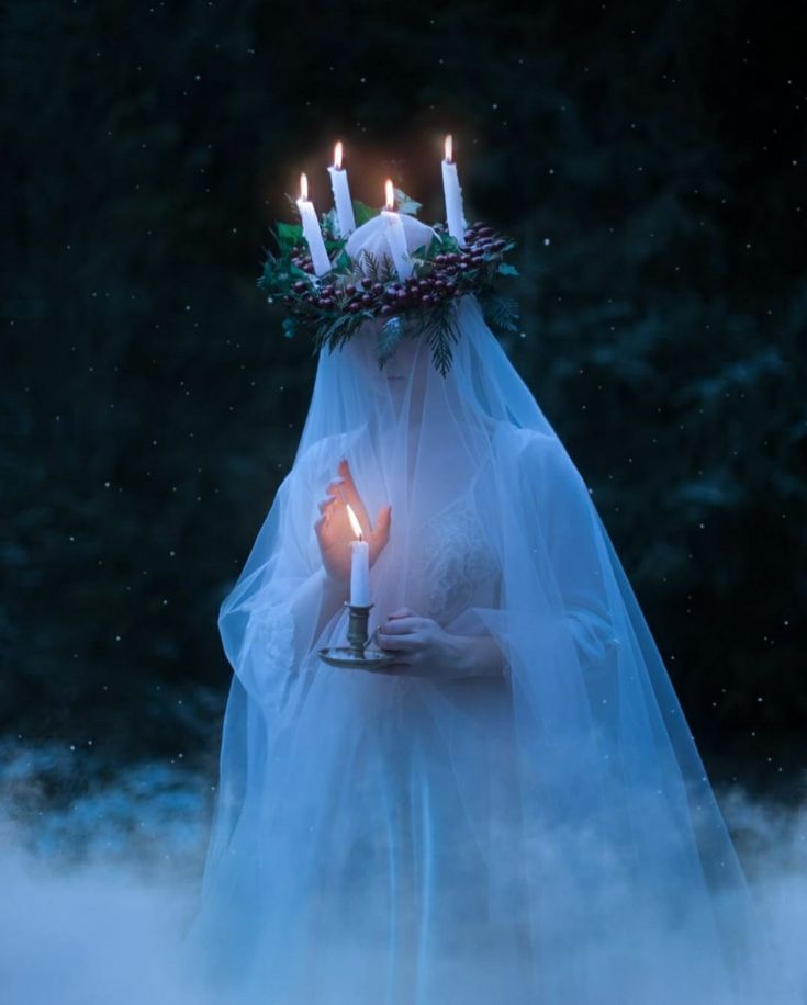 a woman wearing a veil and holding a candle in her hand with fog around her