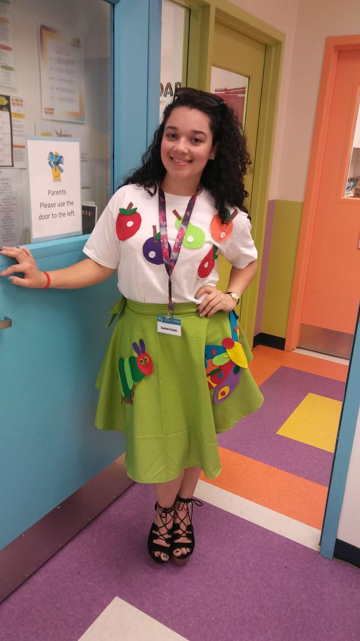 a woman standing in front of a blue door wearing a green skirt and white shirt