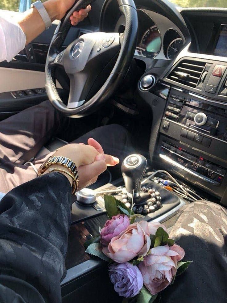 a person is sitting in the driver's seat of a car with flowers on the dashboard