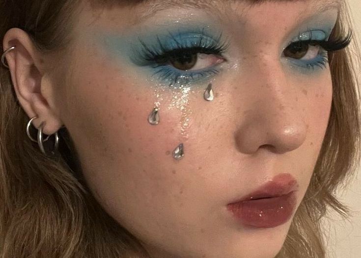 a close up of a woman with blue makeup and teary eyeliners on her face