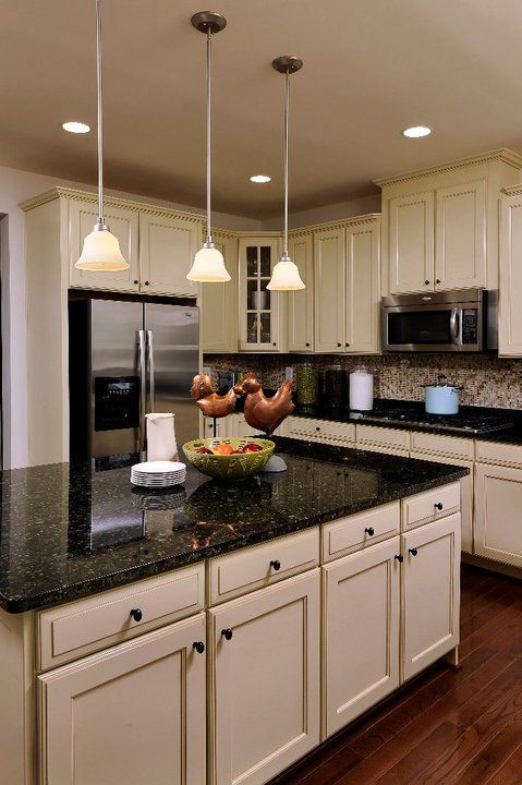 a large kitchen with white cabinets and black counter tops, along with stainless steel appliances