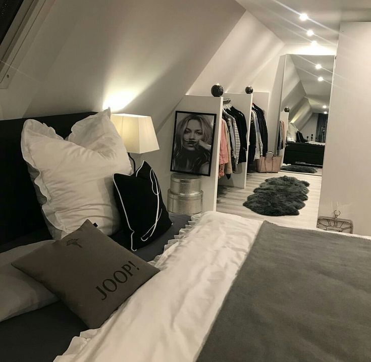 an attic bedroom with white walls and grey bedding, black and white throw pillows