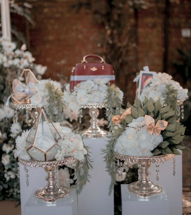 three silver vases filled with flowers on top of a table